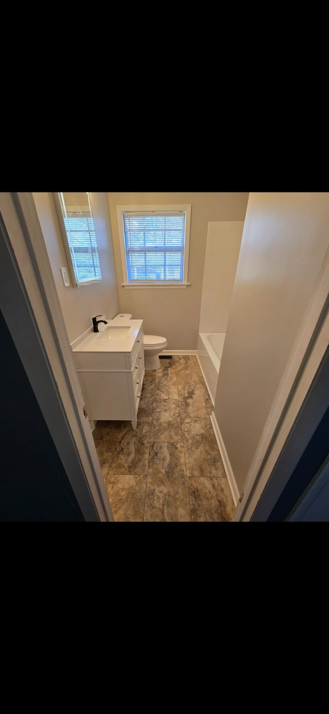 bathroom featuring vanity, toilet, and a tub to relax in