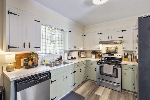 kitchen featuring appliances with stainless steel finishes, light wood-type flooring, ornamental molding, sink, and white cabinets