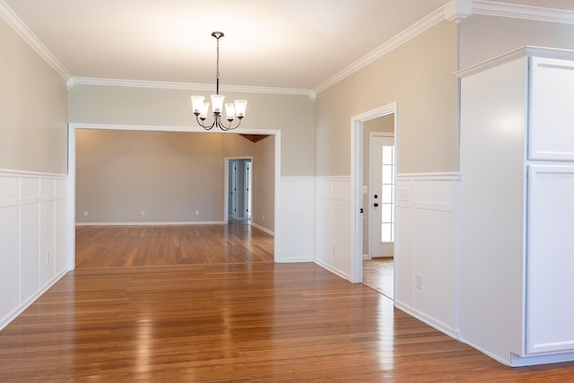 unfurnished dining area featuring an inviting chandelier, ornamental molding, and hardwood / wood-style flooring