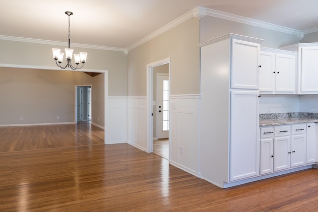 interior space featuring wood-type flooring, white cabinetry, and ornamental molding