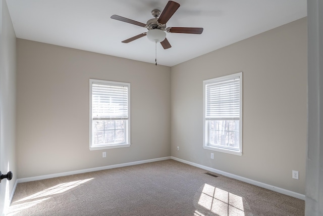 spare room featuring ceiling fan, light colored carpet, and plenty of natural light