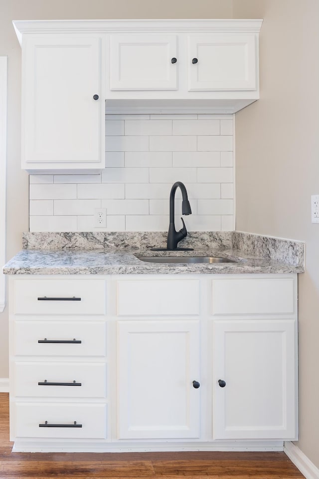 interior space featuring decorative backsplash, sink, and wood-type flooring