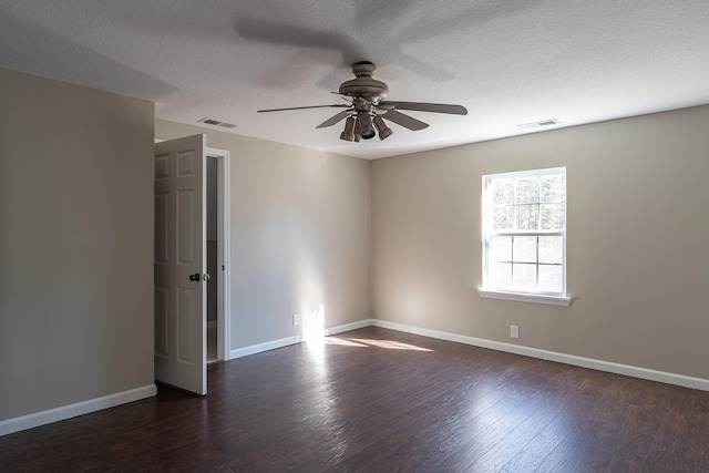 spare room featuring ceiling fan, dark wood-type flooring, and a textured ceiling