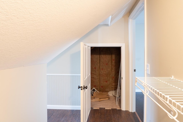 interior space featuring a textured ceiling, dark wood-type flooring, and lofted ceiling