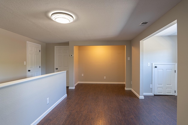 unfurnished room featuring dark wood-type flooring and a textured ceiling