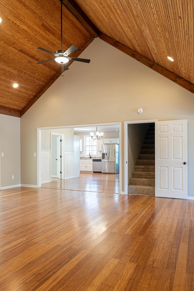 unfurnished living room with ceiling fan with notable chandelier, wooden ceiling, light hardwood / wood-style flooring, and high vaulted ceiling