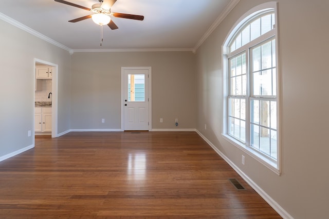 unfurnished room with ceiling fan, dark wood-type flooring, a wealth of natural light, and crown molding