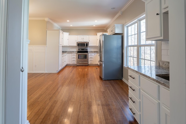 kitchen with backsplash, light hardwood / wood-style floors, white cabinetry, light stone countertops, and appliances with stainless steel finishes