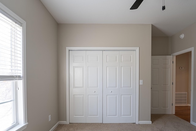 unfurnished bedroom with carpet, a closet, and ceiling fan