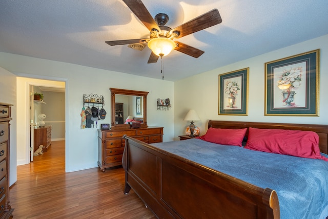 bedroom featuring ceiling fan, hardwood / wood-style floors, and a textured ceiling