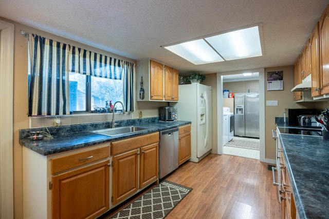 kitchen featuring a textured ceiling, light hardwood / wood-style floors, sink, and appliances with stainless steel finishes