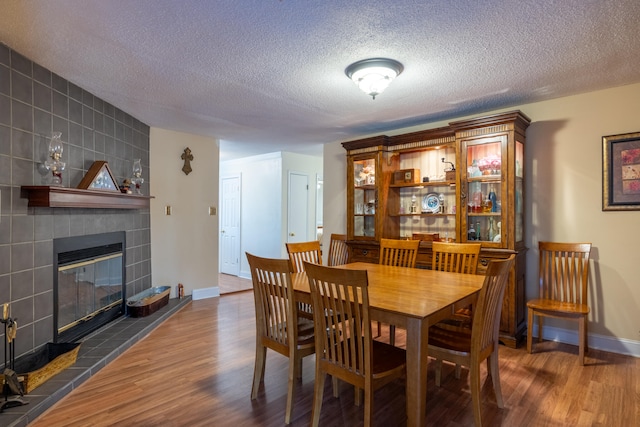 dining space featuring dark hardwood / wood-style floors, a textured ceiling, and a tile fireplace