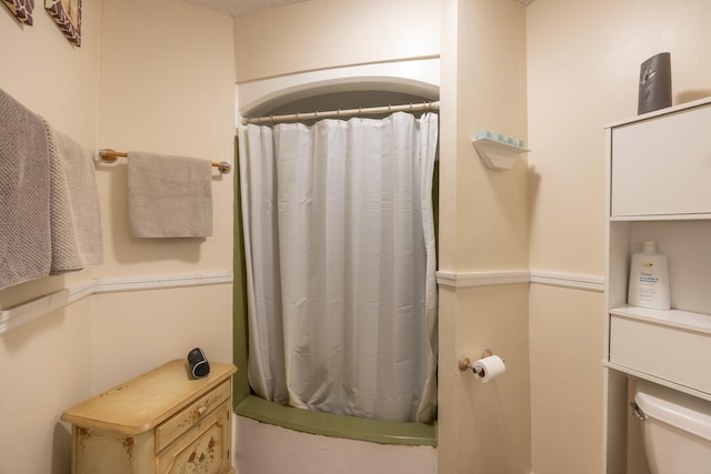 bathroom with curtained shower and toilet