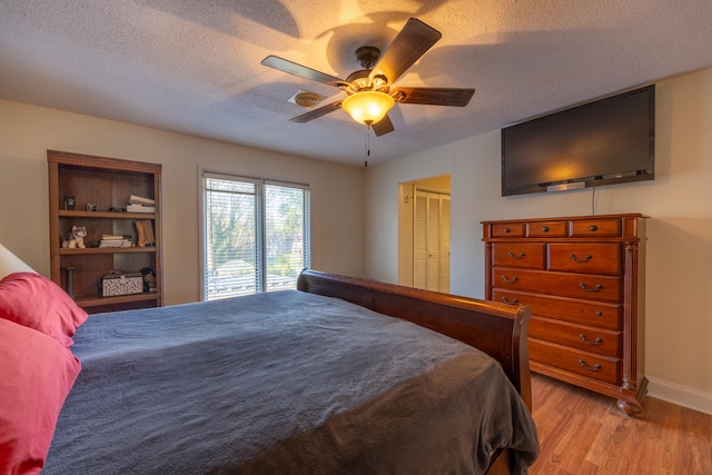 bedroom with ceiling fan, light wood-type flooring, a textured ceiling, and a closet