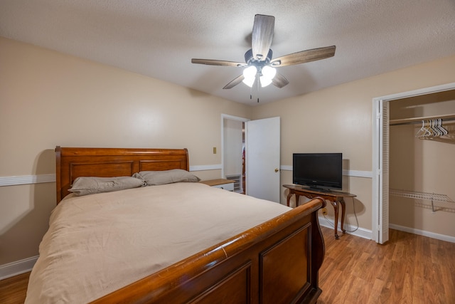 bedroom with ceiling fan, light hardwood / wood-style floors, a textured ceiling, and a closet