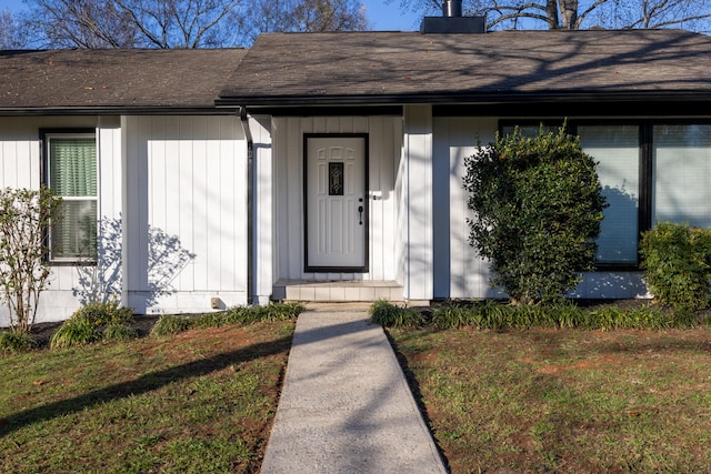 view of exterior entry featuring a lawn