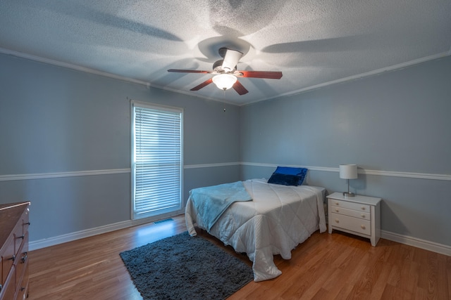 bedroom featuring ceiling fan, ornamental molding, a textured ceiling, and light hardwood / wood-style flooring