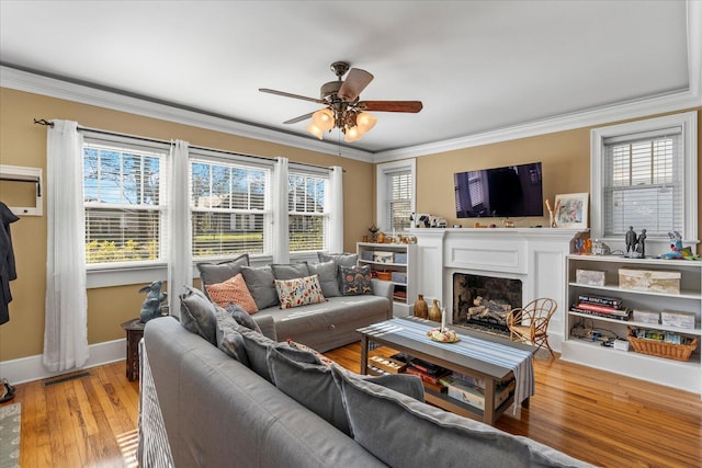 living room featuring ornamental molding, plenty of natural light, and light wood-type flooring