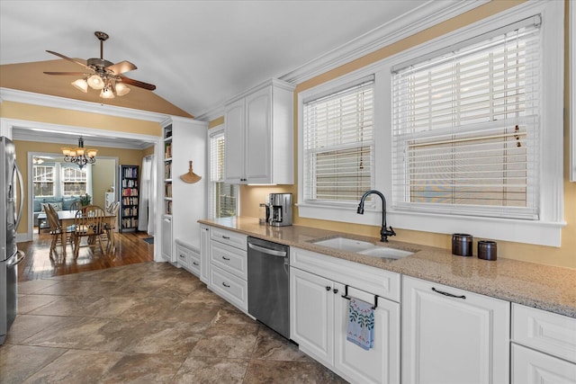 kitchen with vaulted ceiling, appliances with stainless steel finishes, white cabinetry, sink, and light stone counters