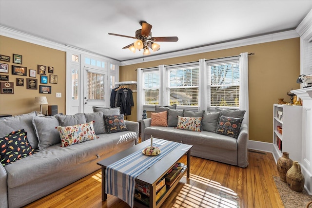 living room with ornamental molding, ceiling fan, and light wood-type flooring