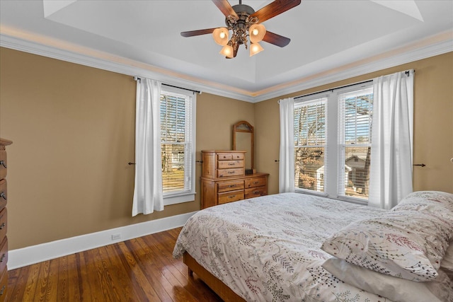 bedroom with multiple windows, ornamental molding, dark wood-type flooring, and a tray ceiling