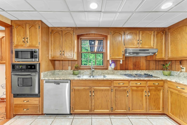 kitchen featuring under cabinet range hood, appliances with stainless steel finishes, light tile patterned flooring, and a sink