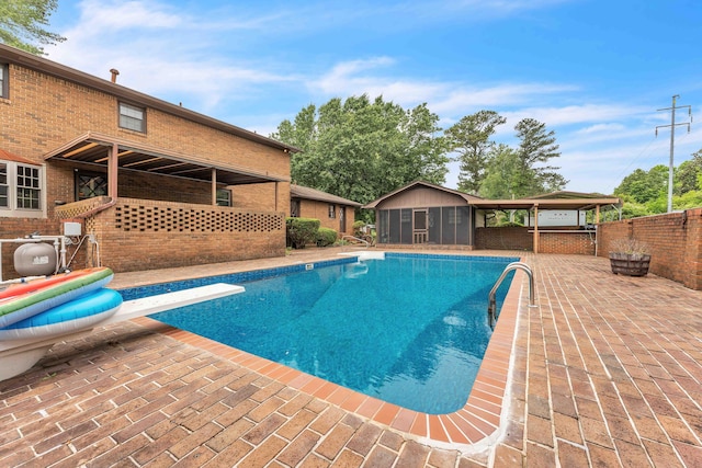 view of swimming pool with a fenced in pool, a diving board, fence, an outdoor structure, and a patio area