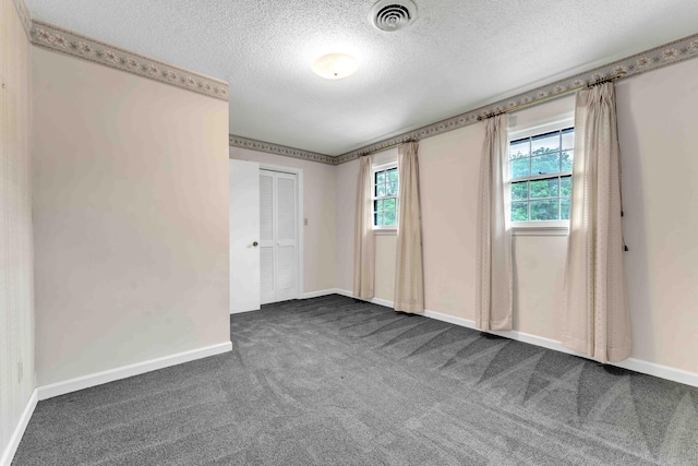 carpeted spare room with baseboards, visible vents, and a textured ceiling