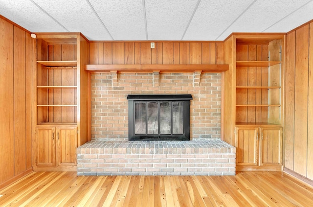 unfurnished living room with hardwood / wood-style flooring, wood walls, and built in shelves