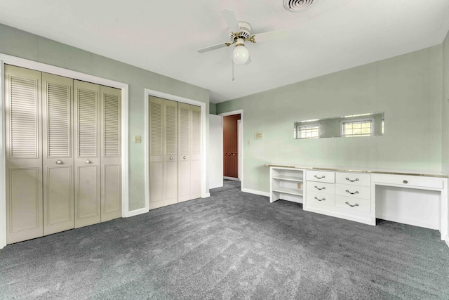 unfurnished bedroom featuring a ceiling fan, baseboards, visible vents, dark carpet, and multiple closets