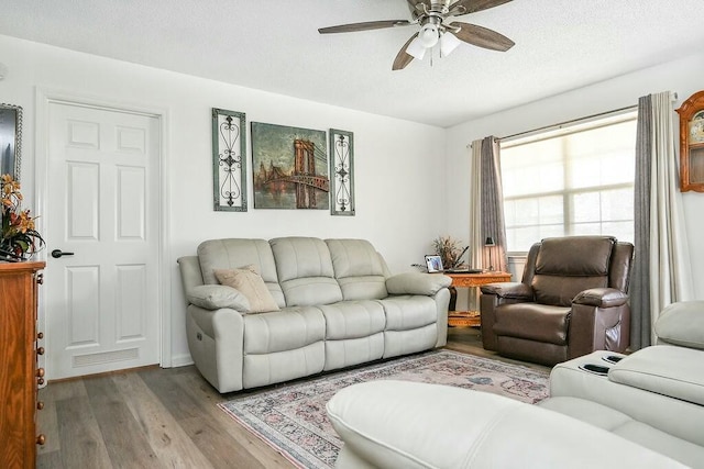 living room with a ceiling fan, wood finished floors, and a textured ceiling