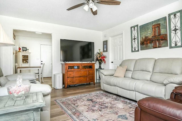 living room featuring a textured ceiling, wood finished floors, and ceiling fan