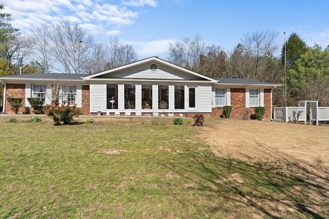 back of property featuring brick siding and a yard