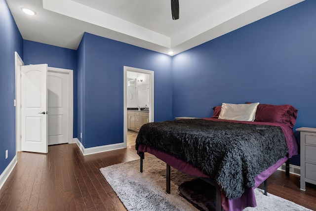 bedroom featuring dark hardwood / wood-style flooring, ceiling fan, and connected bathroom