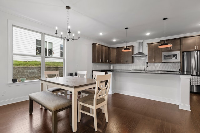 dining space with a chandelier, sink, dark wood-type flooring, and ornamental molding