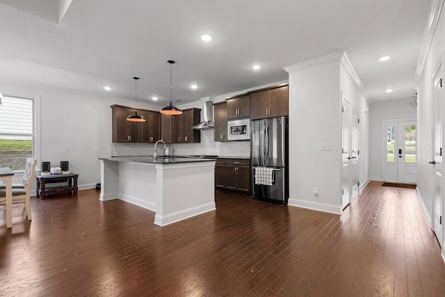 kitchen featuring a center island with sink, wall chimney range hood, dark hardwood / wood-style floors, decorative light fixtures, and stainless steel appliances