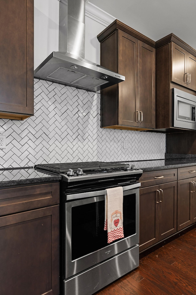 kitchen featuring backsplash, dark wood-type flooring, wall chimney exhaust hood, appliances with stainless steel finishes, and dark brown cabinets