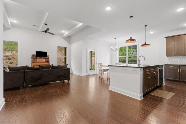 kitchen with decorative backsplash, dark hardwood / wood-style flooring, a center island with sink, and sink