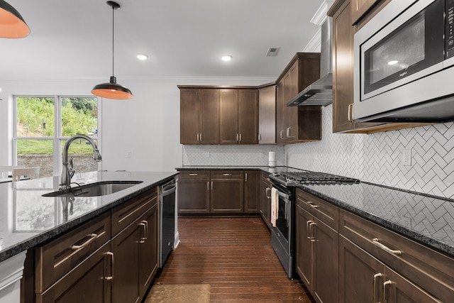 kitchen with appliances with stainless steel finishes, dark wood-type flooring, sink, pendant lighting, and dark stone countertops