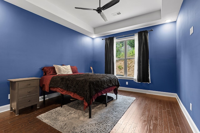 bedroom featuring a raised ceiling, ceiling fan, and dark hardwood / wood-style flooring