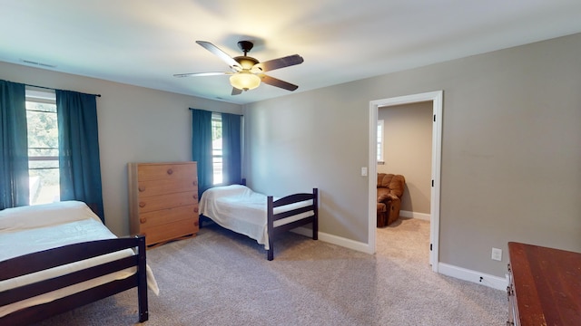 bedroom featuring multiple windows, ceiling fan, and light colored carpet