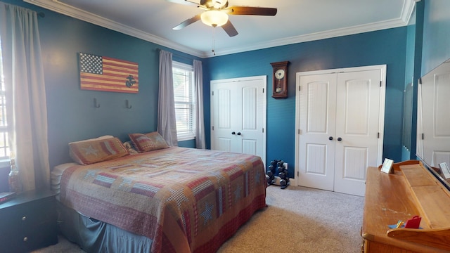 carpeted bedroom featuring ceiling fan, two closets, and ornamental molding