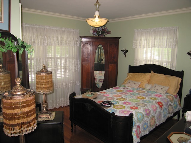 bedroom with dark hardwood / wood-style flooring and ornamental molding