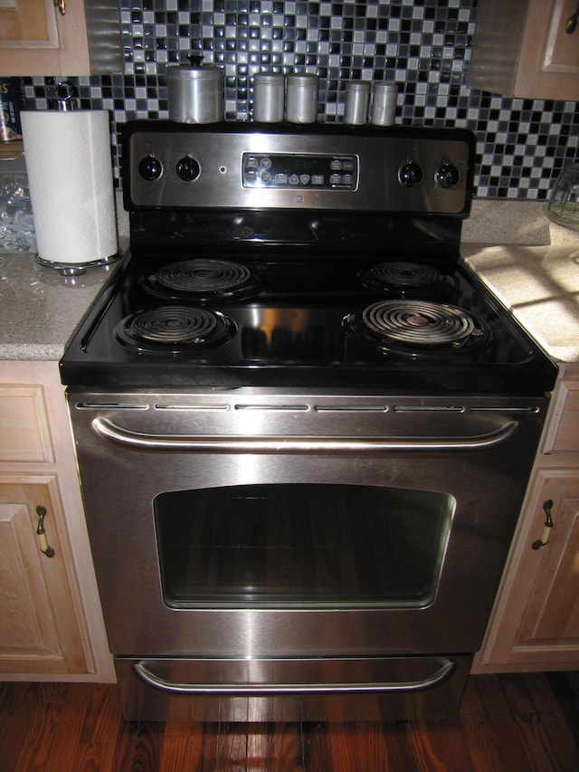 room details featuring light brown cabinetry, dark hardwood / wood-style flooring, and stainless steel range with electric stovetop