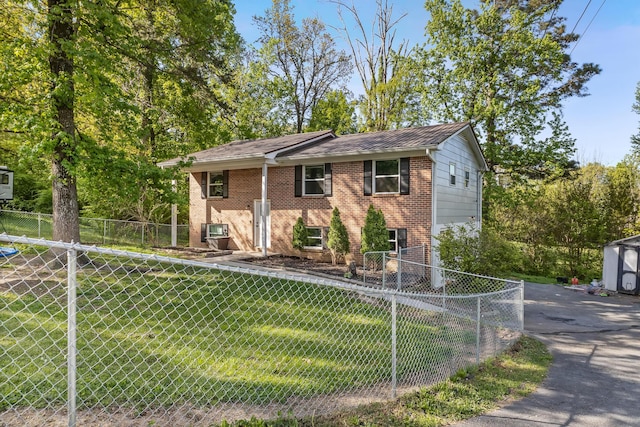 raised ranch featuring brick siding, a front yard, and fence