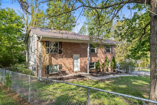rear view of house with a fenced backyard, brick siding, a yard, and metal roof