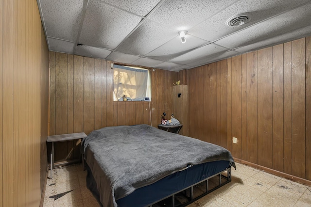 bedroom featuring wood walls, tile patterned floors, a drop ceiling, and visible vents