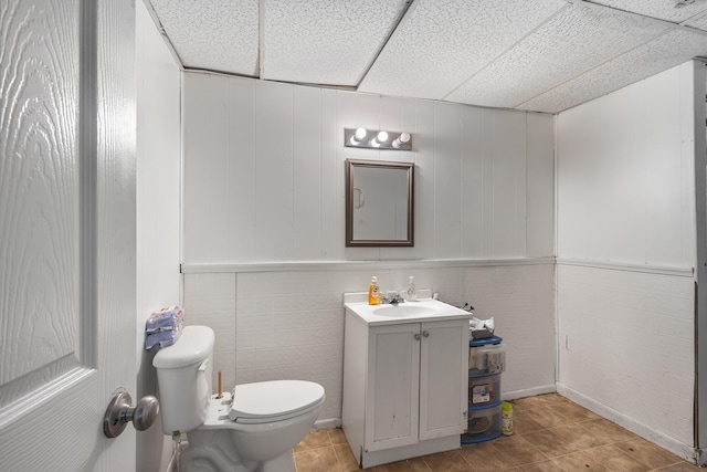 bathroom featuring toilet, vanity, tile patterned floors, and a paneled ceiling