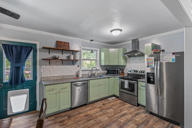 kitchen featuring green cabinetry, heating unit, a sink, wall chimney exhaust hood, and appliances with stainless steel finishes