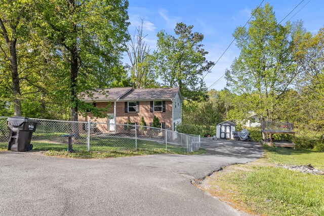 view of front facade featuring fence, an outbuilding, a storage shed, and brick siding